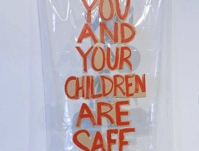 An image of a clear shower curtain with the words “you and your children are safe here” written in red paint