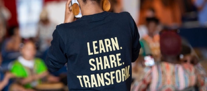 Woman wearing a shirt saying "learn. share. transform."
