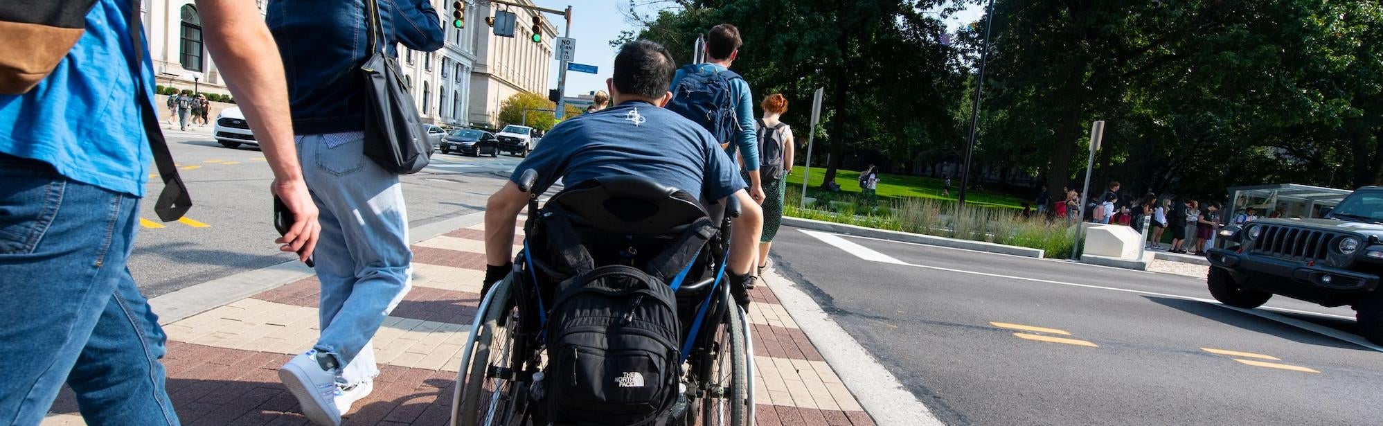 A picture of a group of people crossing Bigelow Boulevard on the Pittsburgh campus.